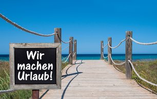 Schild "wir machen Urlaub" am Strand 